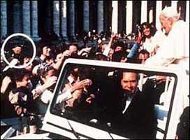 A hand holding a gun aims from the crowd at Pope John Paul II as he rides through St. Peter's Square on May 13, 1981.
