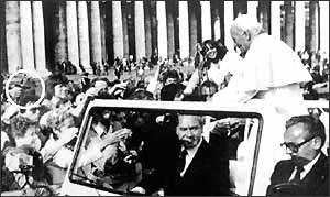 A hand holding a gun aims from the crowd at Pope John Paul II as he rides through St. Peter's Square on May 13, 1981, the Feast Day of our Lady of Fatima. An instant later he was shot.